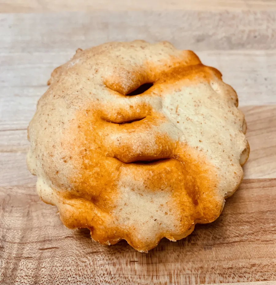 A whole golden round savory pie on a wooden board